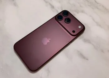 iPhone China Marktanteil: dunkelrotes iPhone aus der Pro-Reihe von hinten auf einer hellen Marmorfläche, mit Kameraplateau und drei Objektiven