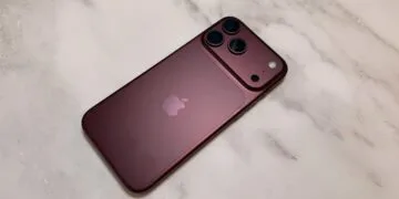 iPhone China Marktanteil: dunkelrotes iPhone aus der Pro-Reihe von hinten auf einer hellen Marmorfläche, mit Kameraplateau und drei Objektiven