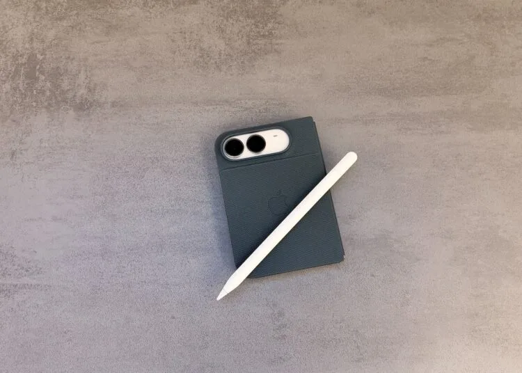 Zugeklapptes iPhone Duo in einer dunklen Hülle auf einer grauen Steinoberfläche, darauf ein weißer Apple Pencil – so sieht das iPhone Duo mit Apple Pencil aus