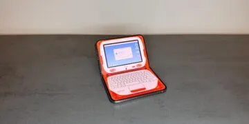 Eine der angepassten iPhone Duo Apps verwandelt das halb aufgeklappte iPhone Duo auf einem Tisch in einen orangefarbenen Retro-Laptop mit Bildschirm oben und Tastatur unten.