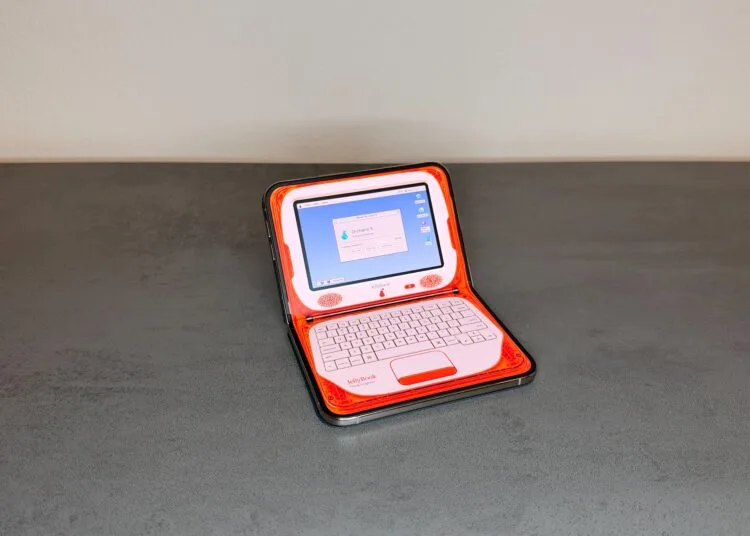 Eine der angepassten iPhone Duo Apps verwandelt das halb aufgeklappte iPhone Duo auf einem Tisch in einen orangefarbenen Retro-Laptop mit Bildschirm oben und Tastatur unten.
