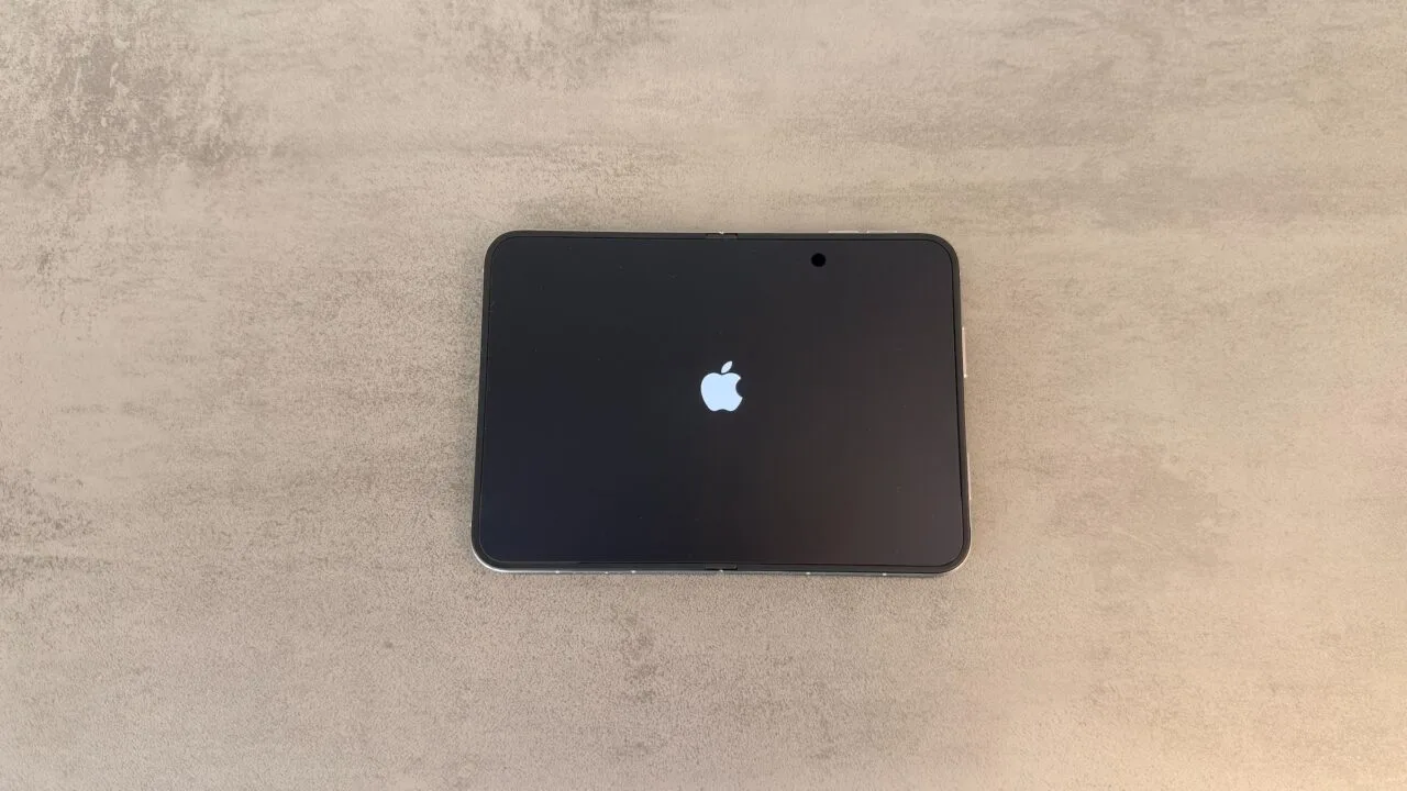 iPhone Duo Rückruf: aufgeklapptes iPhone Duo liegt flach auf einem grauen Tisch, das Innendisplay zeigt beim Start das Apple-Logo