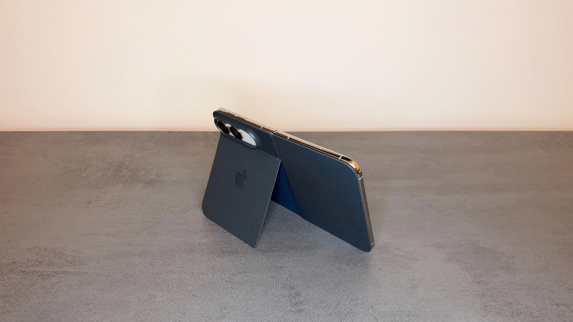 iPhone Duo im blauen Folio, aufgestellt über den ausgeklappten Aufsteller, Teil des ersten Eindrucks im Alltag