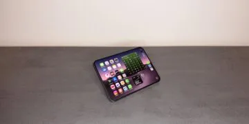 iPhone Duo Widgets auf dem Home-Bildschirm: aufgeklapptes iPhone Duo im Querformat auf einem grauen Tisch, links App-Symbole, rechts Widgets mit Spielplan und Börsenkurs
