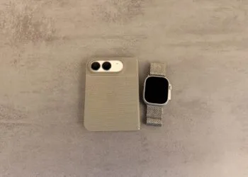 iPhone Duo mit Apple Watch entsperren: zugeklapptes iPhone Duo in einer Hülle mit Blick auf die Kamera neben einer Apple Watch Ultra mit Milanaise-Armband auf grauer Steinoberfläche