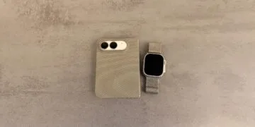 iPhone Duo mit Apple Watch entsperren: zugeklapptes iPhone Duo in einer Hülle mit Blick auf die Kamera neben einer Apple Watch Ultra mit Milanaise-Armband auf grauer Steinoberfläche