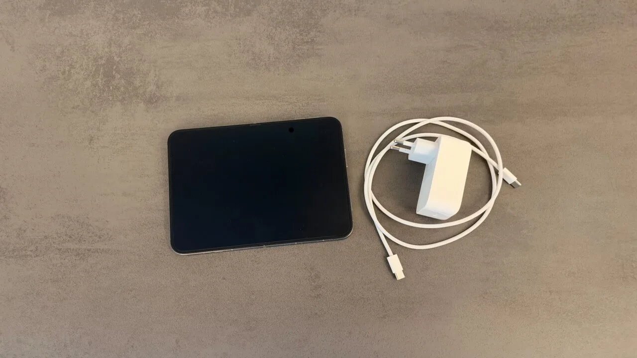 iPhone Duo schnell laden: aufgeklapptes iPhone Duo auf einer grauen Steinoberfläche, daneben ein weißes USB-C-Netzteil und ein geflochtenes USB-C-Ladekabel