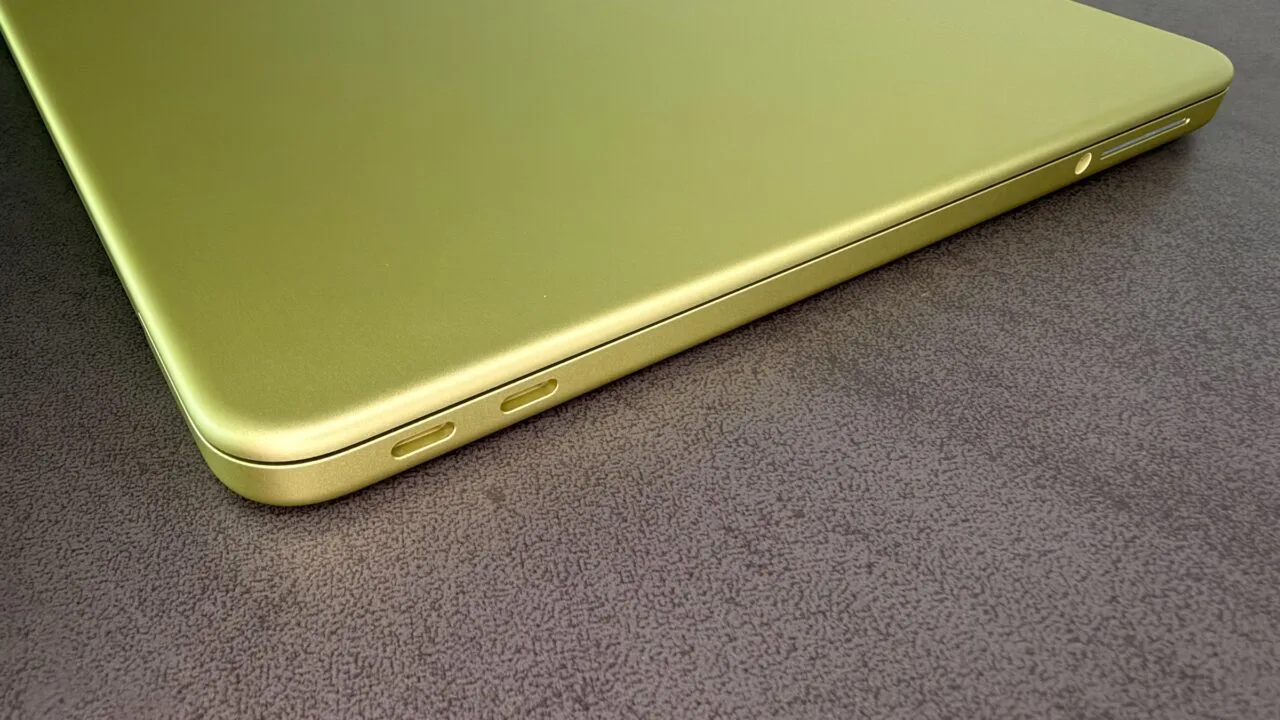 Zugeklapptes MacBook Neo in Citrus mit zwei USB-C-Anschlüssen auf einer dunklen Tischplatte, zum steigenden Mac-Marktanteil im schrumpfenden PC-Markt