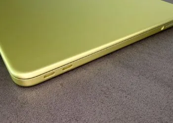 Zugeklapptes MacBook Neo in Citrus mit zwei USB-C-Anschlüssen auf einer dunklen Tischplatte, zum steigenden Mac-Marktanteil im schrumpfenden PC-Markt