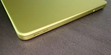 Zugeklapptes MacBook Neo in Citrus mit zwei USB-C-Anschlüssen auf einer dunklen Tischplatte, zum steigenden Mac-Marktanteil im schrumpfenden PC-Markt