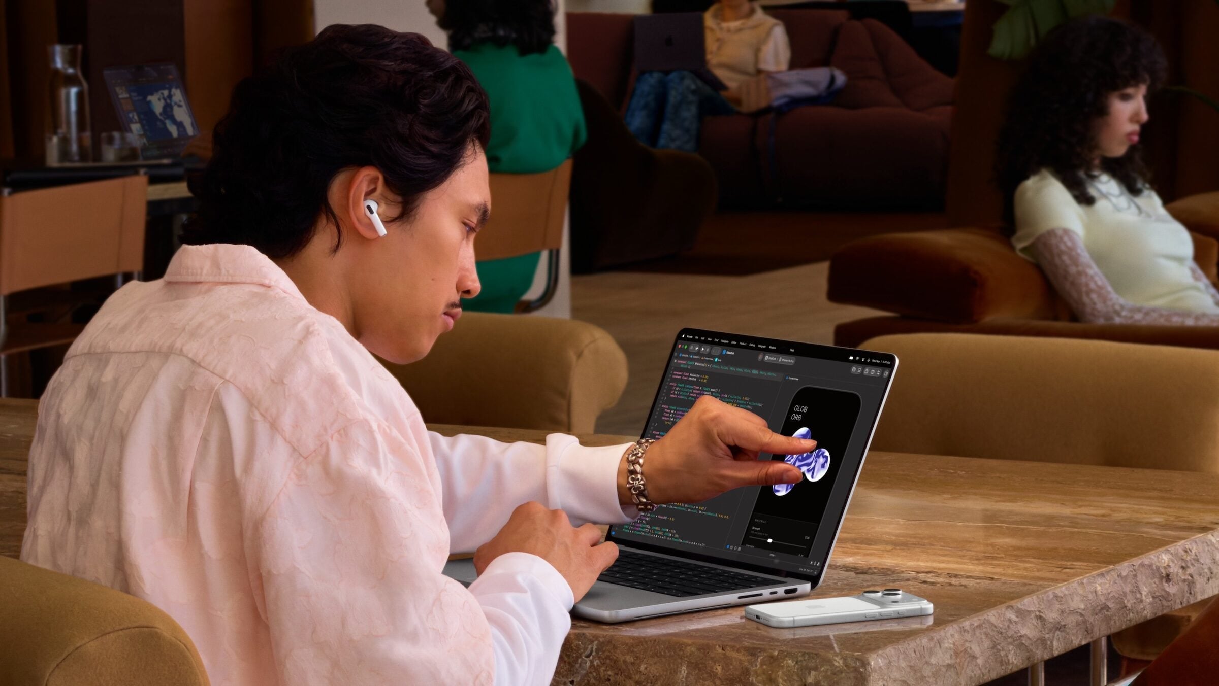 MacBook Pro PROLED XDR vs. Mini-LED: a man at a table uses his finger on the touch display of a silver MacBook Pro with PROLED XDR display
