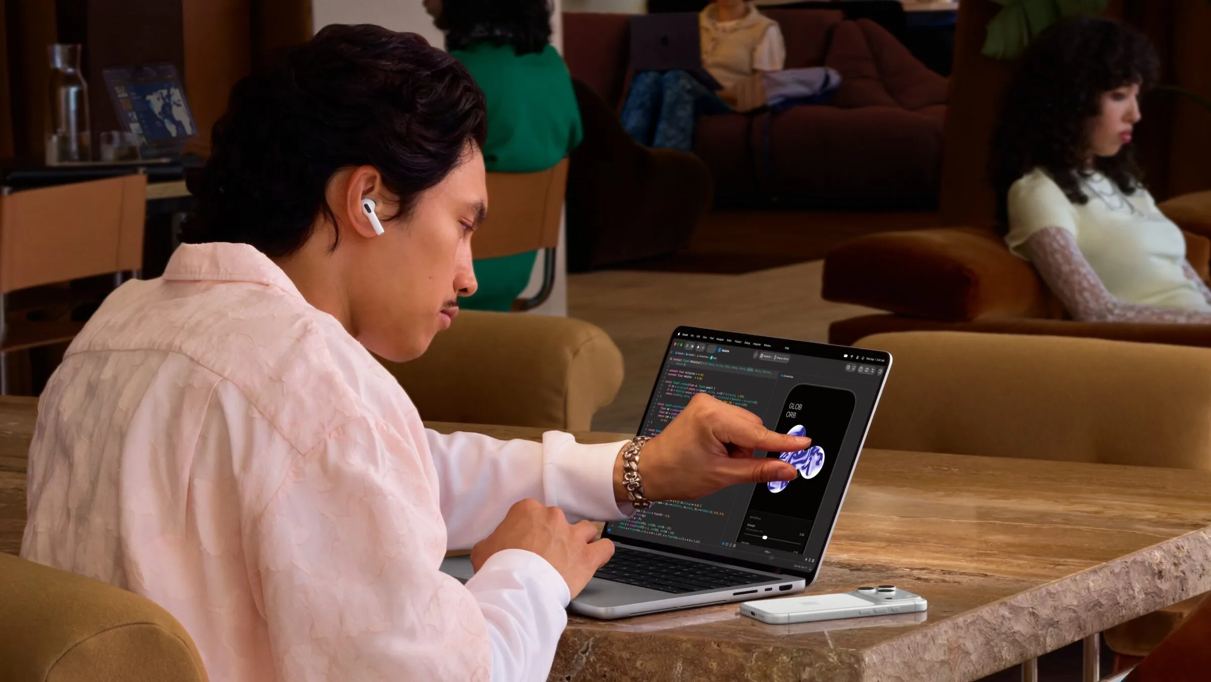 MacBook Pro PROLED XDR vs. Mini-LED: Ein Mann bedient an einem Tisch das Touch-Display eines MacBook Pro mit PROLED XDR Display in Silber mit dem Finger