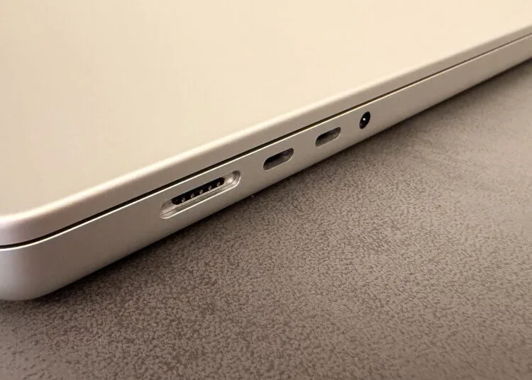 Silbernes MacBook auf einer dunklen Tischplatte, Blick auf MagSafe-Anschluss, zwei USB-C-Anschlüsse und Kopfhörerbuchse – Symbolbild zum Notebook-Markt 2027