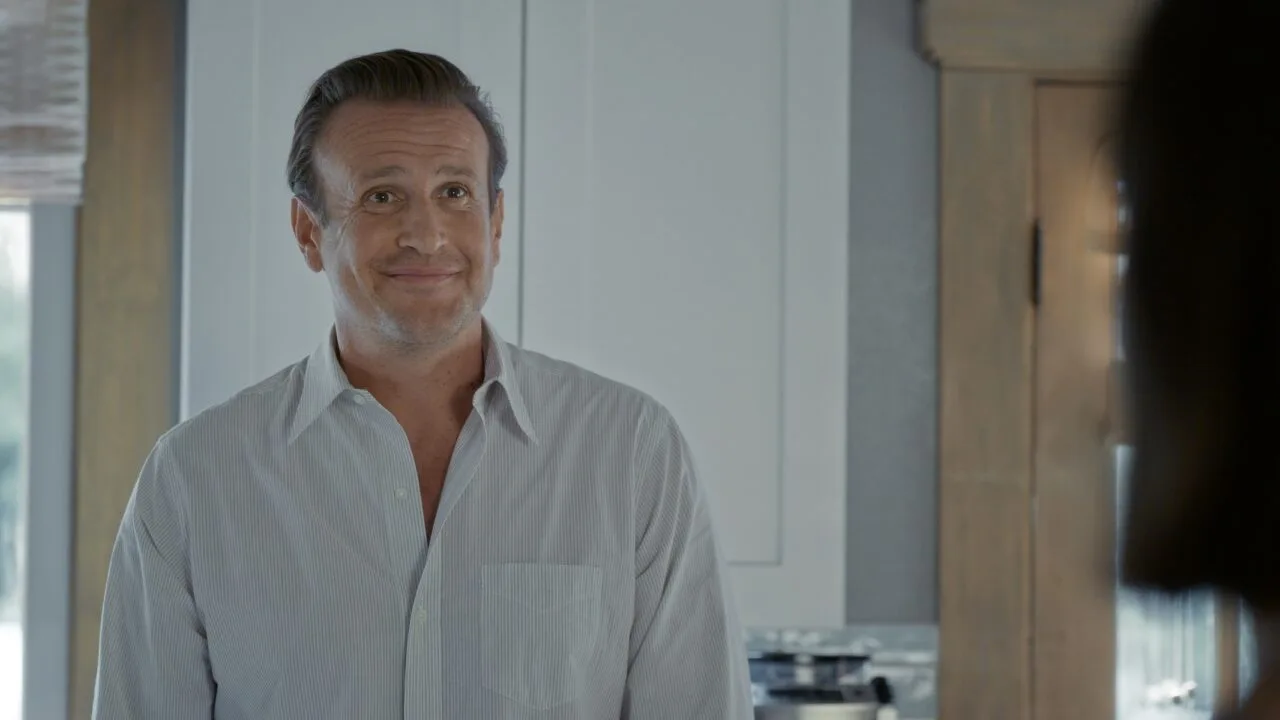 Vor Shrinking Staffel 4: Jason Segel als Jimmy in einer früheren Folge, lächelnd in einer Küche, rechts unscharf eine Person im Vordergrund