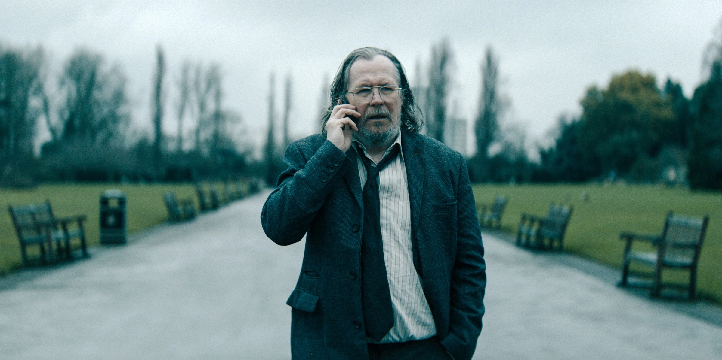 Gary Oldman als Jackson Lamb telefoniert in einem regnerischen Park – Szene aus Staffel 6 vor dem Slow Horses Finale