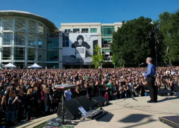 Gedenkfeier nach dem Steve Jobs Todestag 2011: Tim Cook spricht vor Tausenden Mitarbeitern auf dem Apple-Campus, im Hintergrund ein großes Porträt von Steve Jobs mit Macintosh