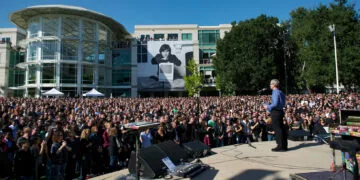 Gedenkfeier nach dem Steve Jobs Todestag 2011: Tim Cook spricht vor Tausenden Mitarbeitern auf dem Apple-Campus, im Hintergrund ein großes Porträt von Steve Jobs mit Macintosh