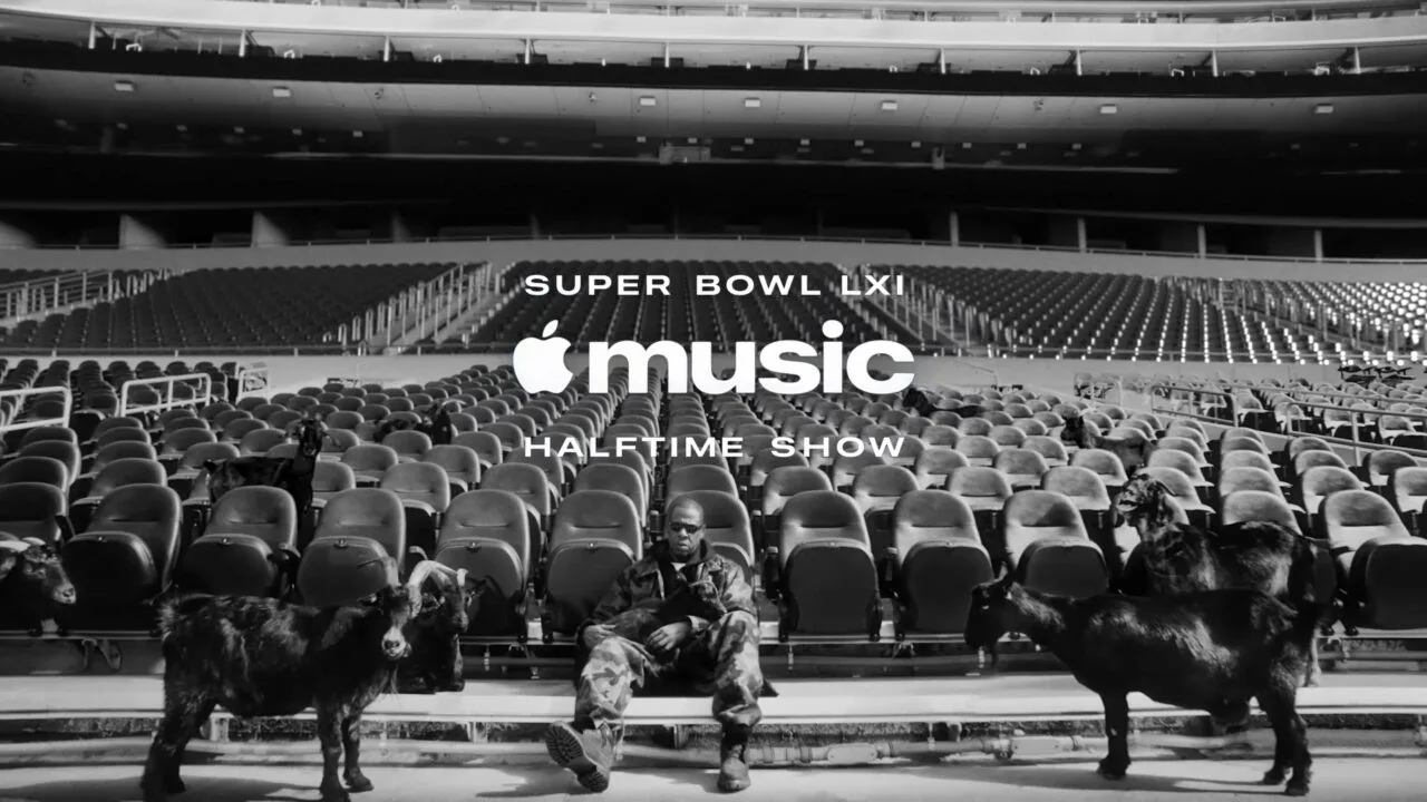 Super Bowl LXI Jay-Z: Der Rapper sitzt in Tarnkleidung auf einer leeren Stadiontribüne zwischen schwarzen Ziegen, darüber der Schriftzug der Apple Music Halftime Show