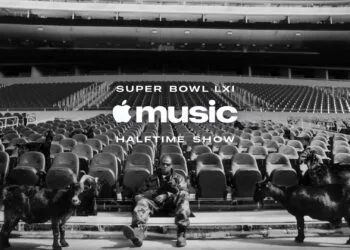 Super Bowl LXI Jay-Z: Der Rapper sitzt in Tarnkleidung auf einer leeren Stadiontribüne zwischen schwarzen Ziegen, darüber der Schriftzug der Apple Music Halftime Show