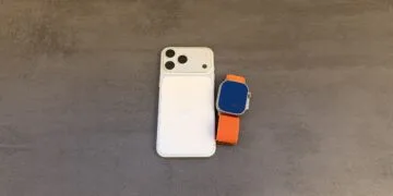 Taptic Engine Patentstreit: iPhone in Weiß mit Dreifachkamera von hinten, daneben eine Apple Watch Ultra mit orangefarbenem Alpine Loop auf grauem Untergrund